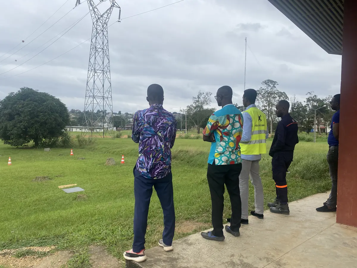 Stagiaires en formation devant un pylône électrique, sur le terrain