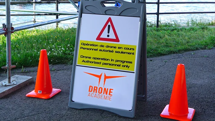 Panneau de signalisation « Opération de drone en cours, personnel autorisé seulement » entre deux cônes
