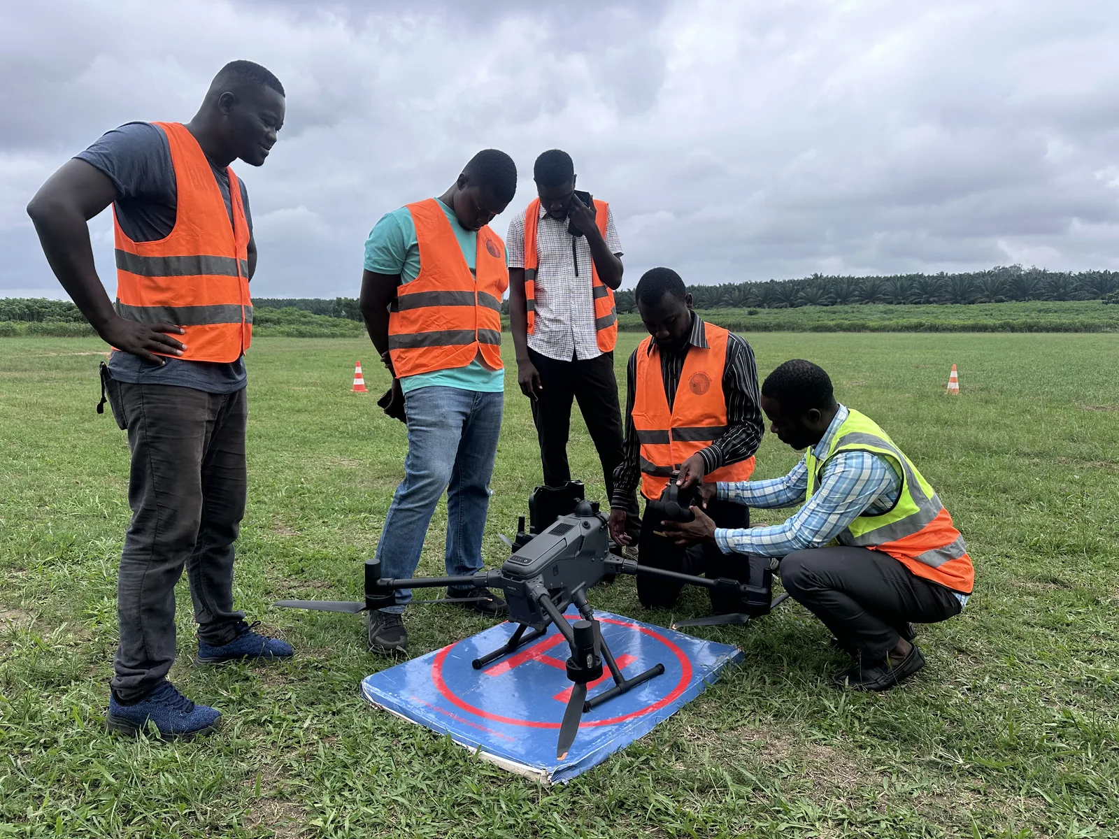 Groupe de stagiaires en gilet de sécurité autour d'un drone sur l'aire de décollage